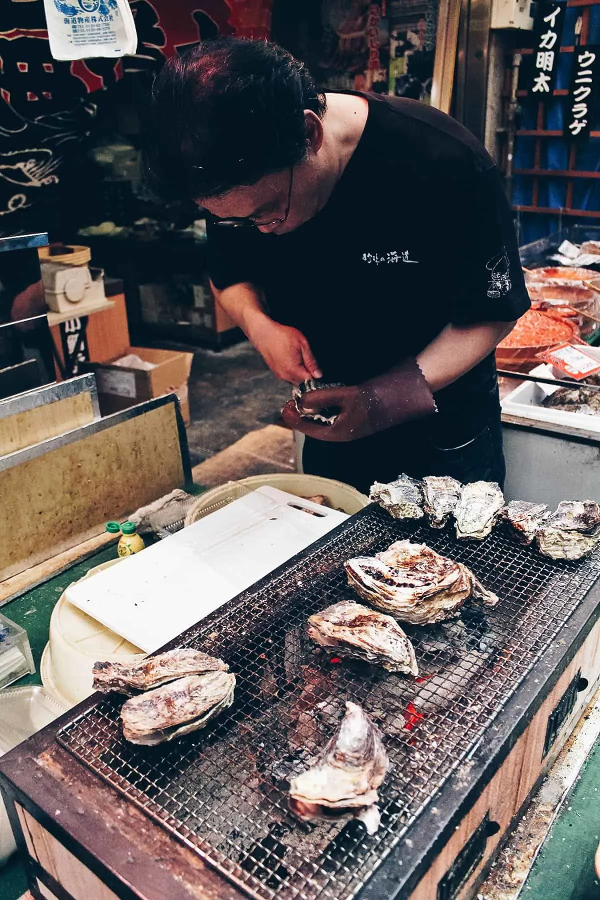 Man shucking oyster at Kuromon Ichiba Market