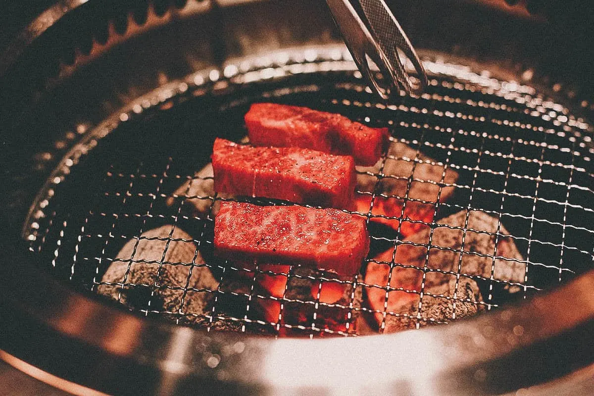 Sliced beef grilling over charcoal at a Japanese yakiniku restaurant in Osaka
