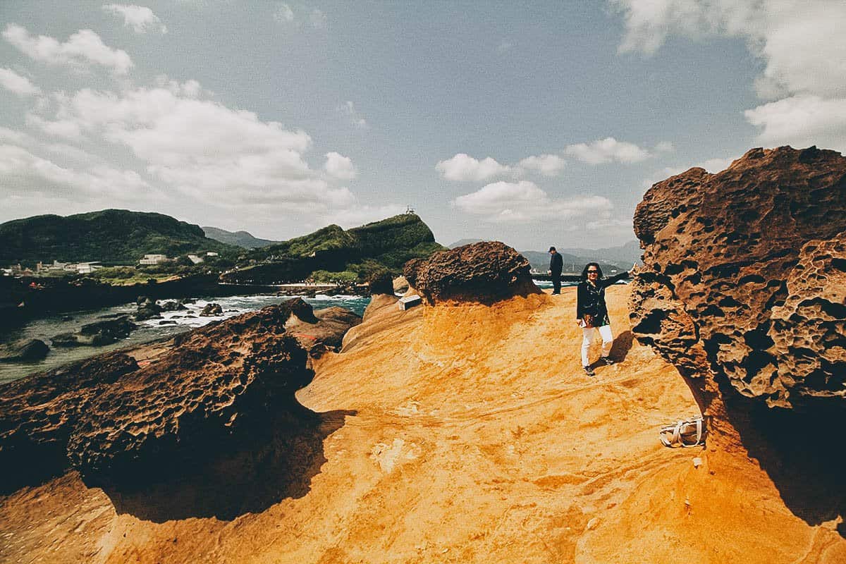 Woman posing next to hoodoo stone in Yehliu Geopark, New Taipei City, Taiwan