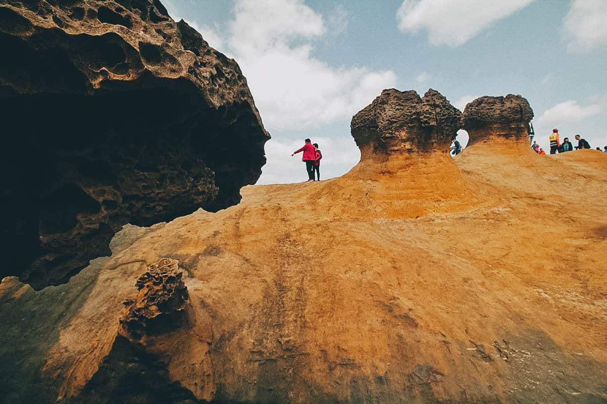 Tourists between rock formations at Yehliu Geopark, New Taipei City, Taiwan