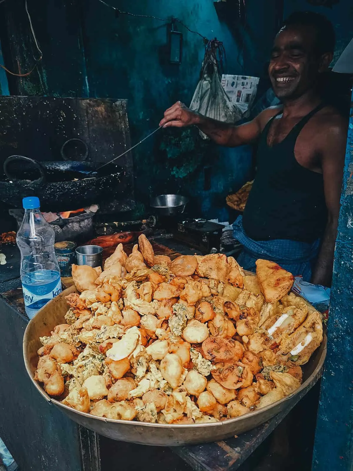 Indian man selling pakoras made with green chilies, onions, potatoes, paneer, etc