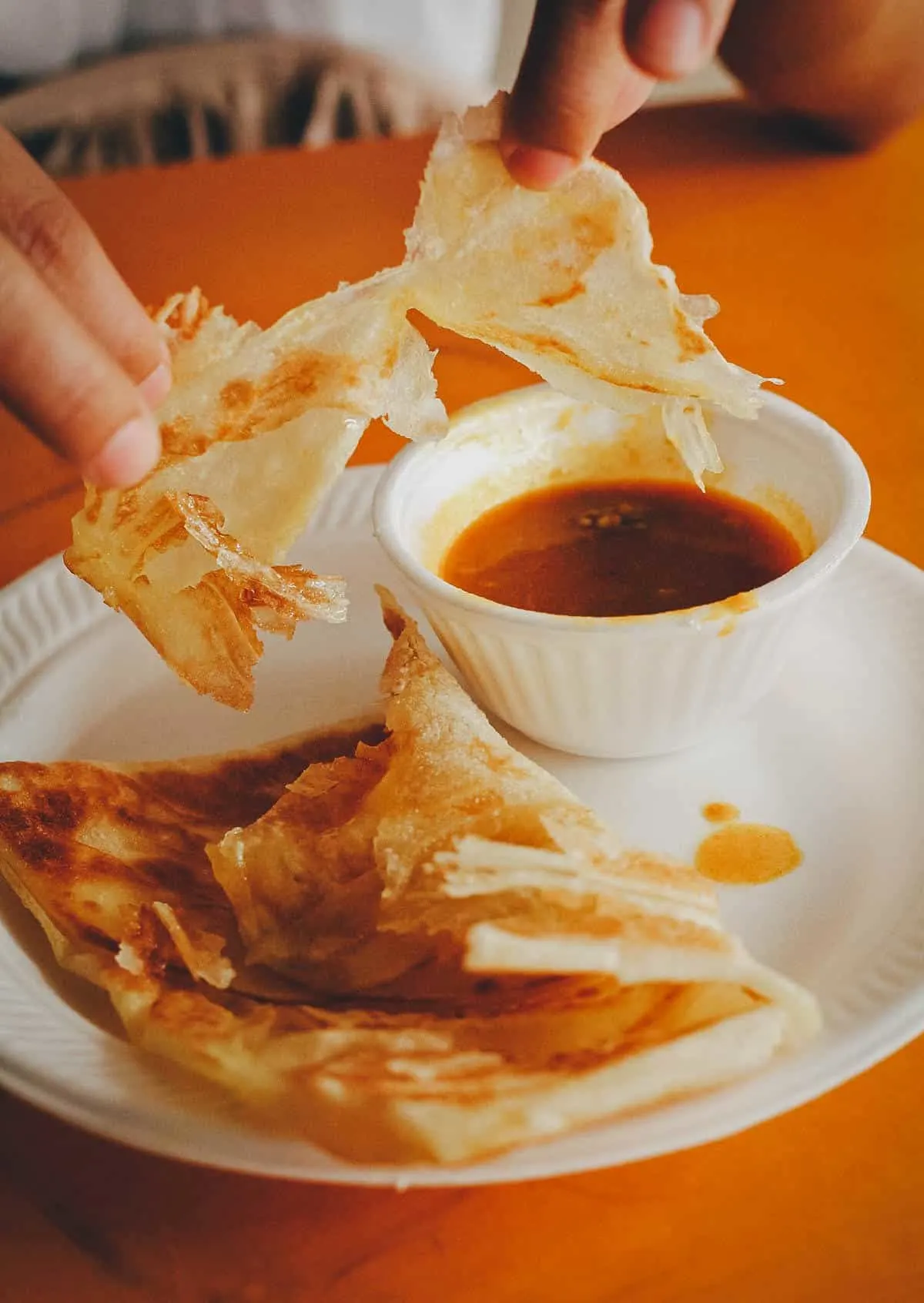 Tearing apart roti prata at Tekka Hawker Center in Singapore