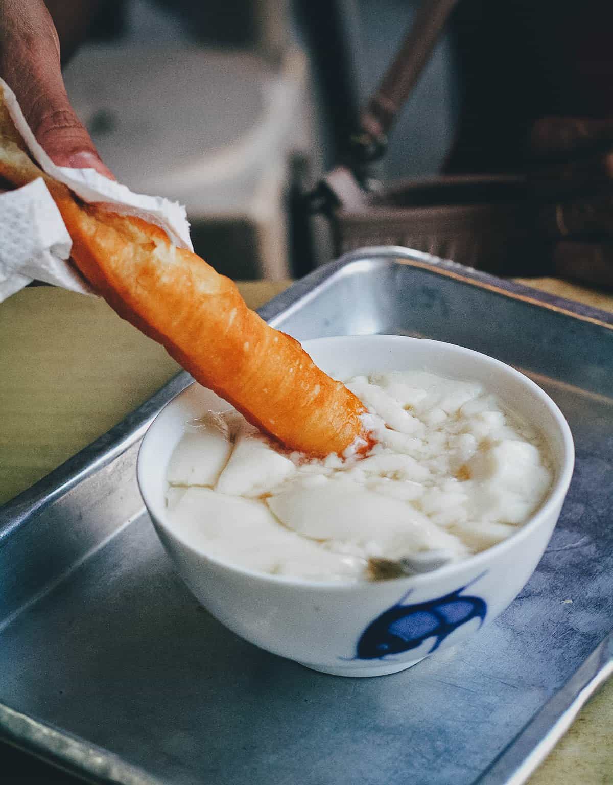 Dipping the dough stick in the bean curd in Singapore