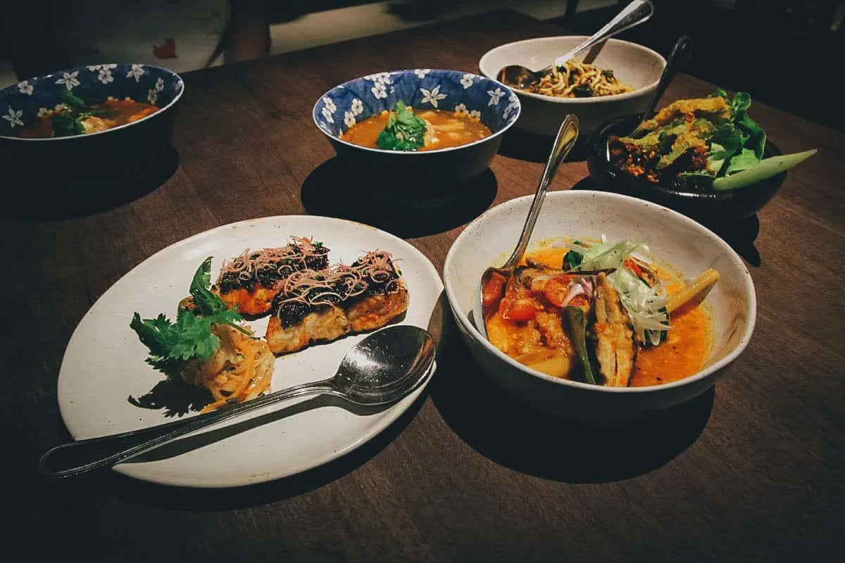 The 25 Best Restaurants in Singapore Dining room table full of Peranakan dishes from Candlenut's Michelin-starred tasting menu