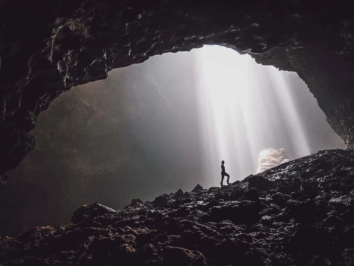 Person under light from hole in cave