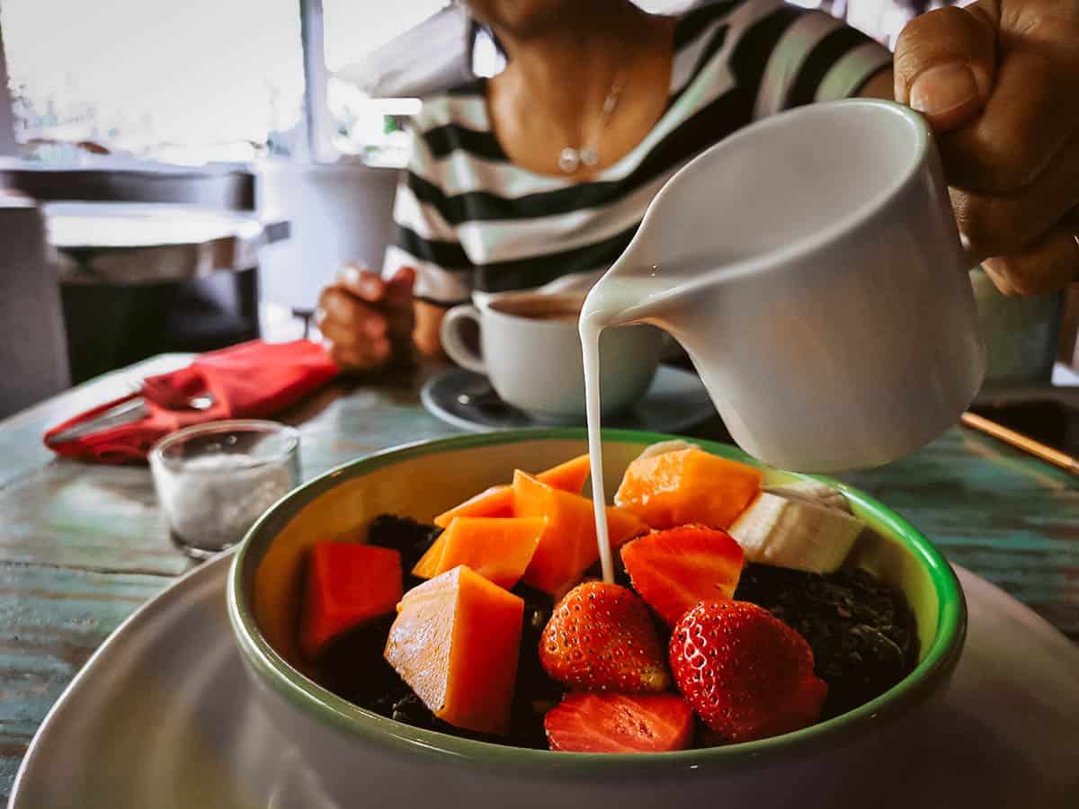 Pouring milk into a fruit bowl at a cafe restaurant in Bali