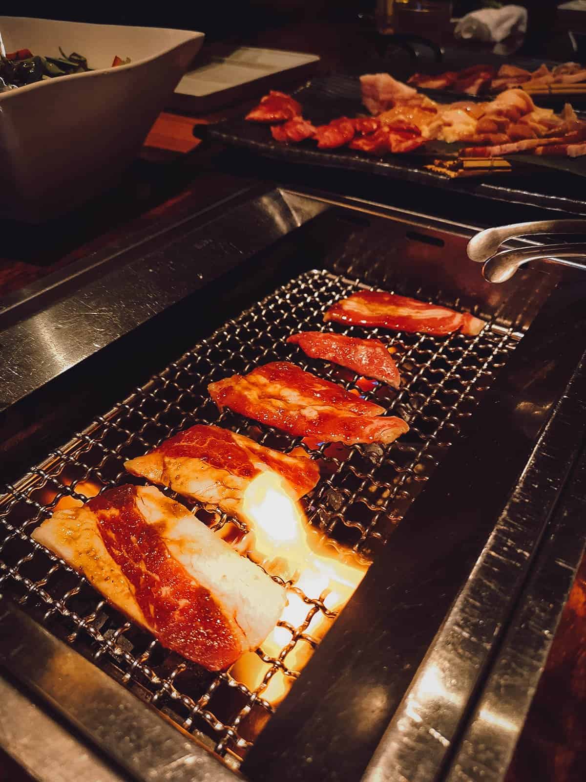 Grilling meat at Yakiniku Nurubon in Fukuoka