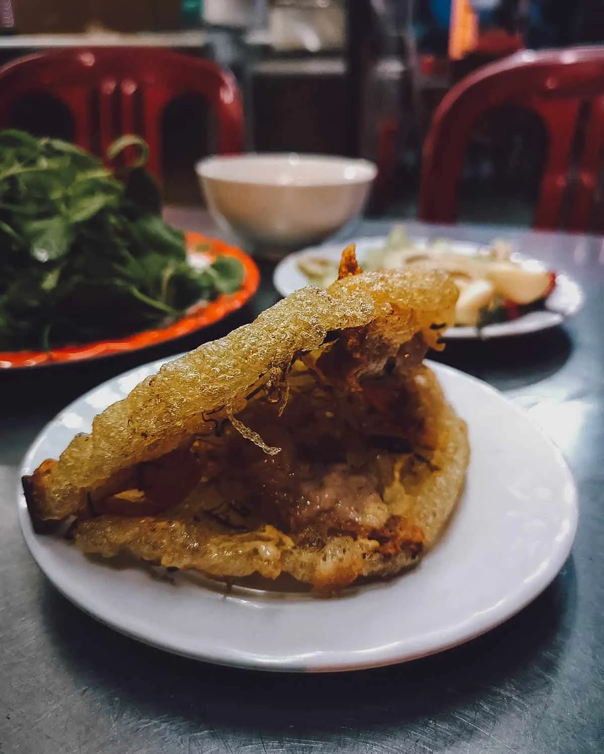 Banh khoai with fresh herbs and bean sprouts, a popular Vietnamese street food in Hue similar to bánh xèo