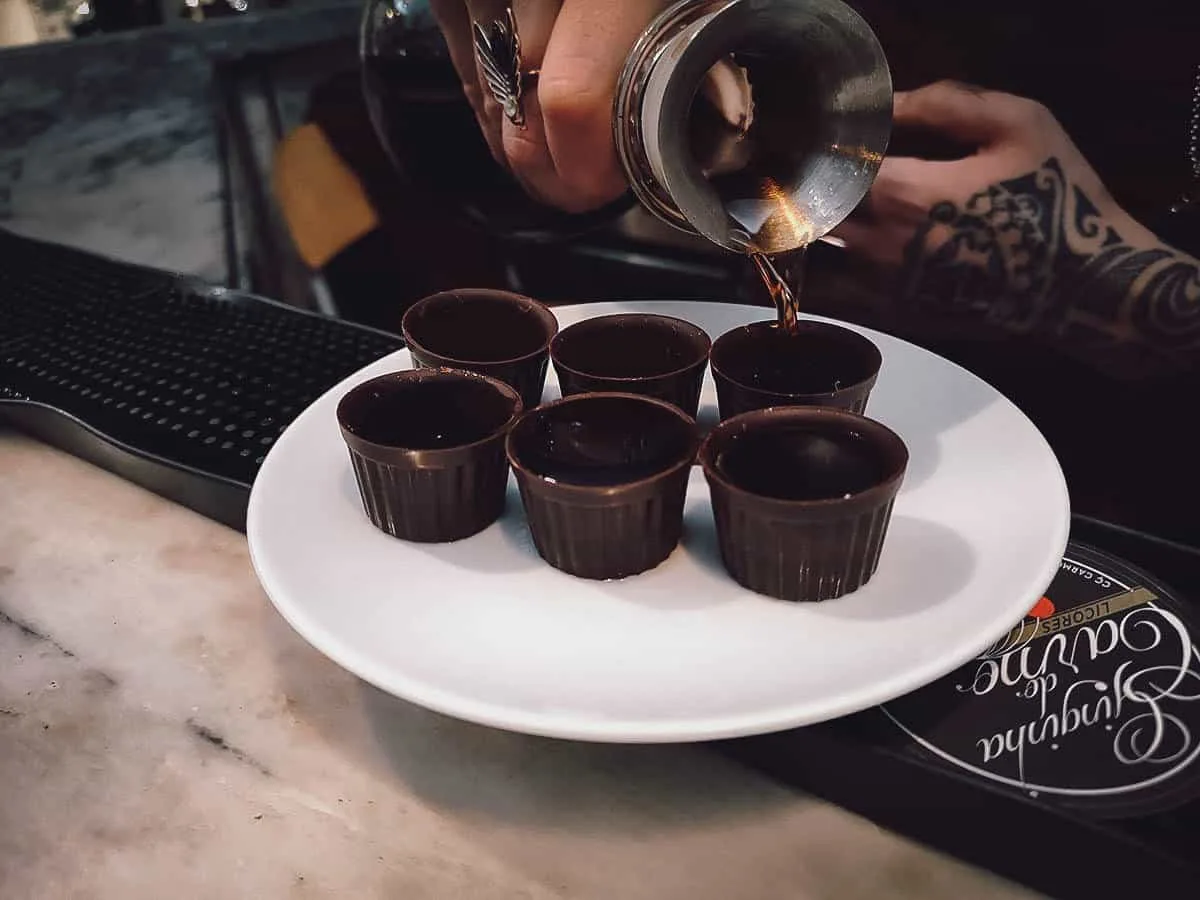 Portuguese Desserts Pouring ginjinha in edible chocolate cups at a bar in Lisbon