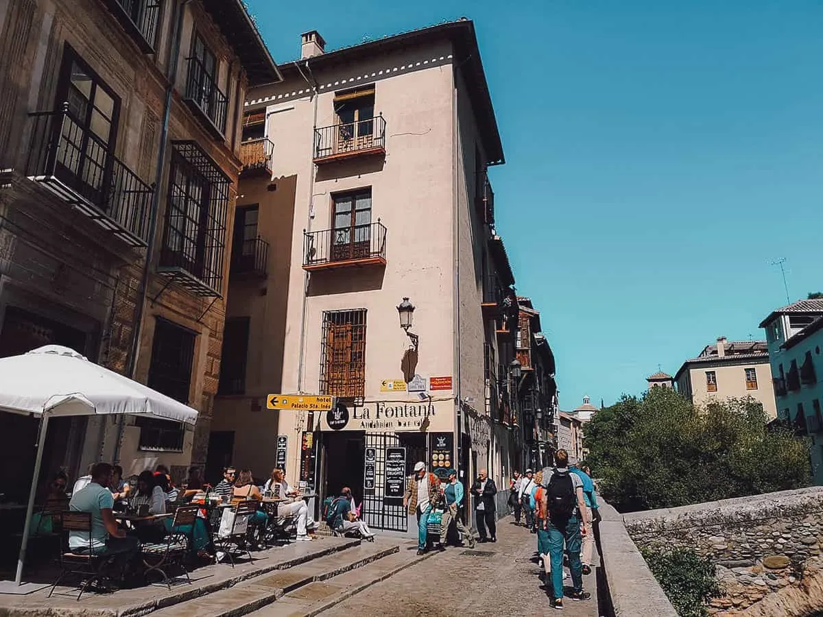 People walking along Calle Carrera del Darro in Granada, Spain