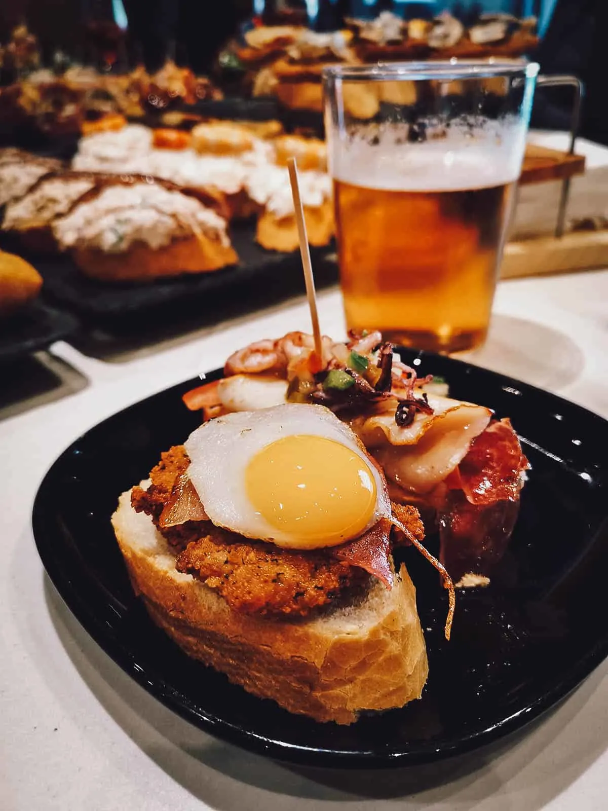 Pair of pintxos on a plate with beer