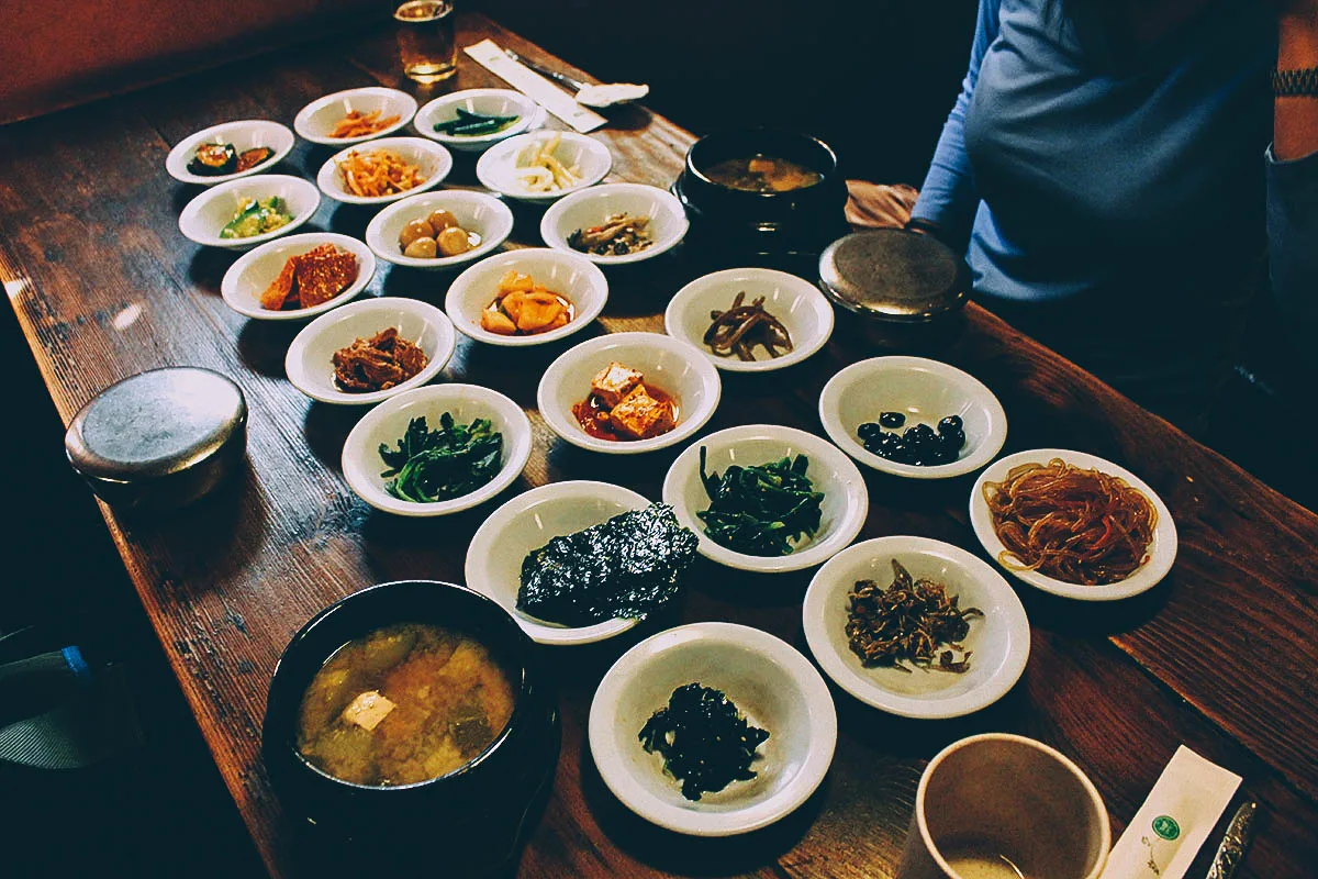Kimchi stew and a set of Korean side dishes with fermented, steamed, and stir-fried vegetables