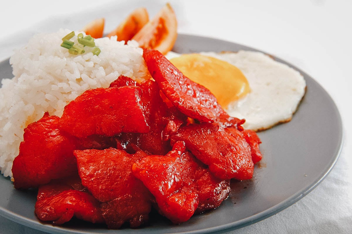 Filipino silog breakfast dish with tocino, fried garlic rice, and a fried egg