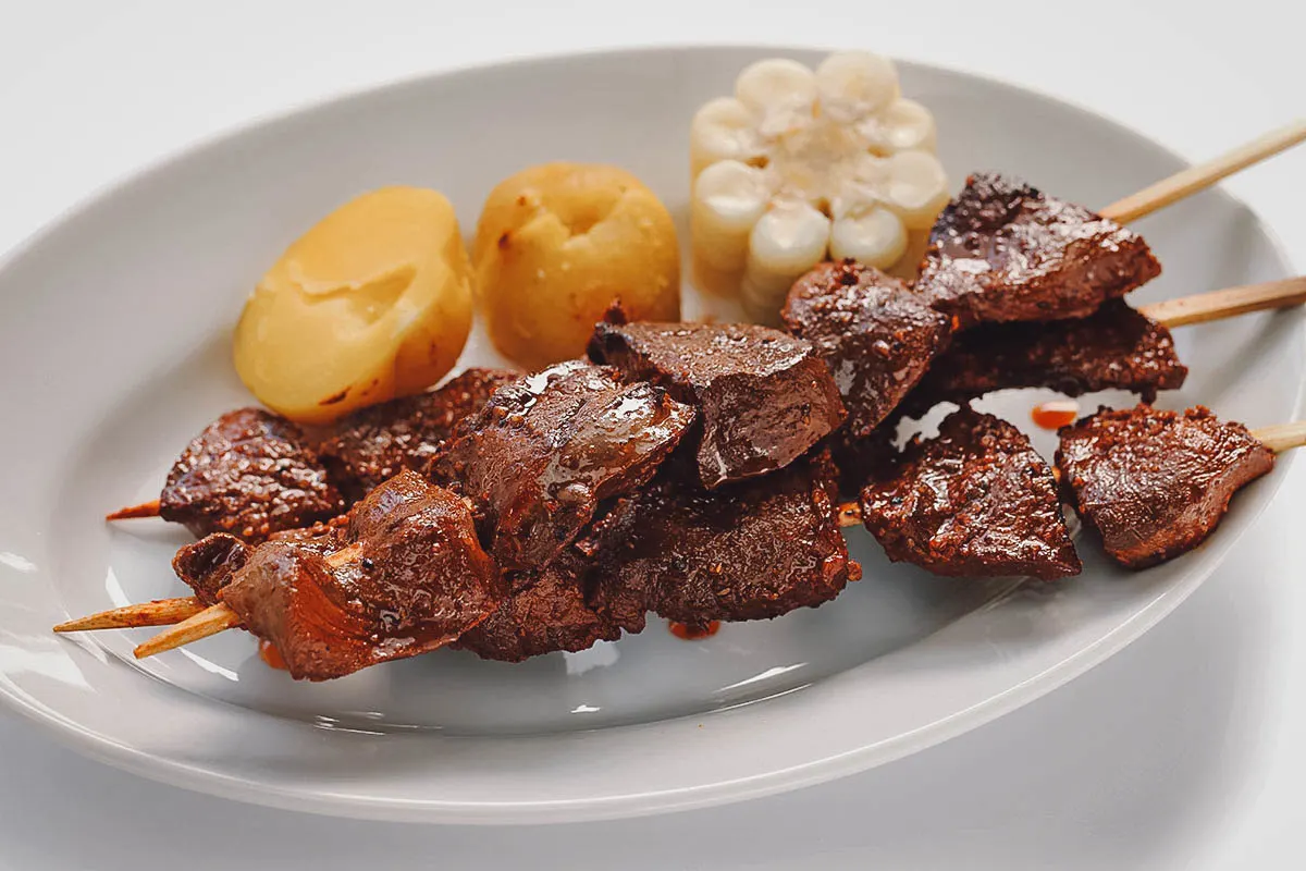 Peruvian Food Anticuchos, a popular Peruvian street food made from beef heart, served with potatoes and corn