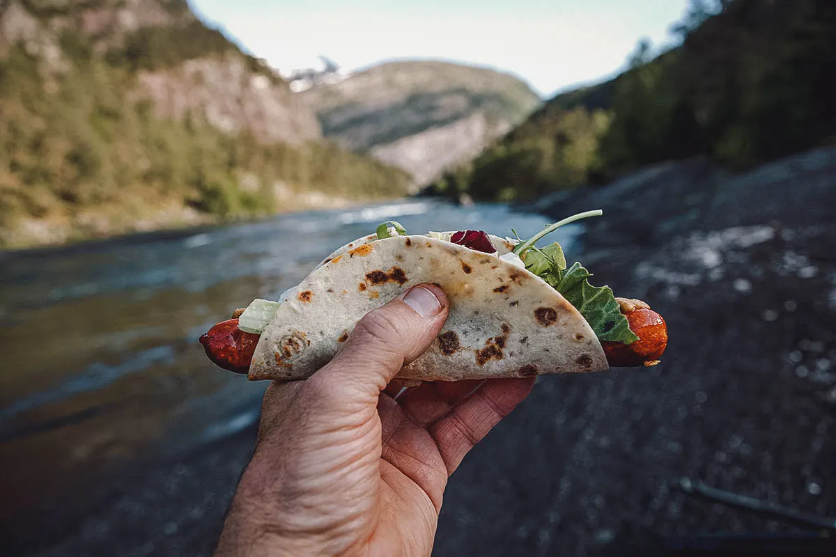 Norwegian Food Man holding polse med lompe, a type of Norwegian hot dog