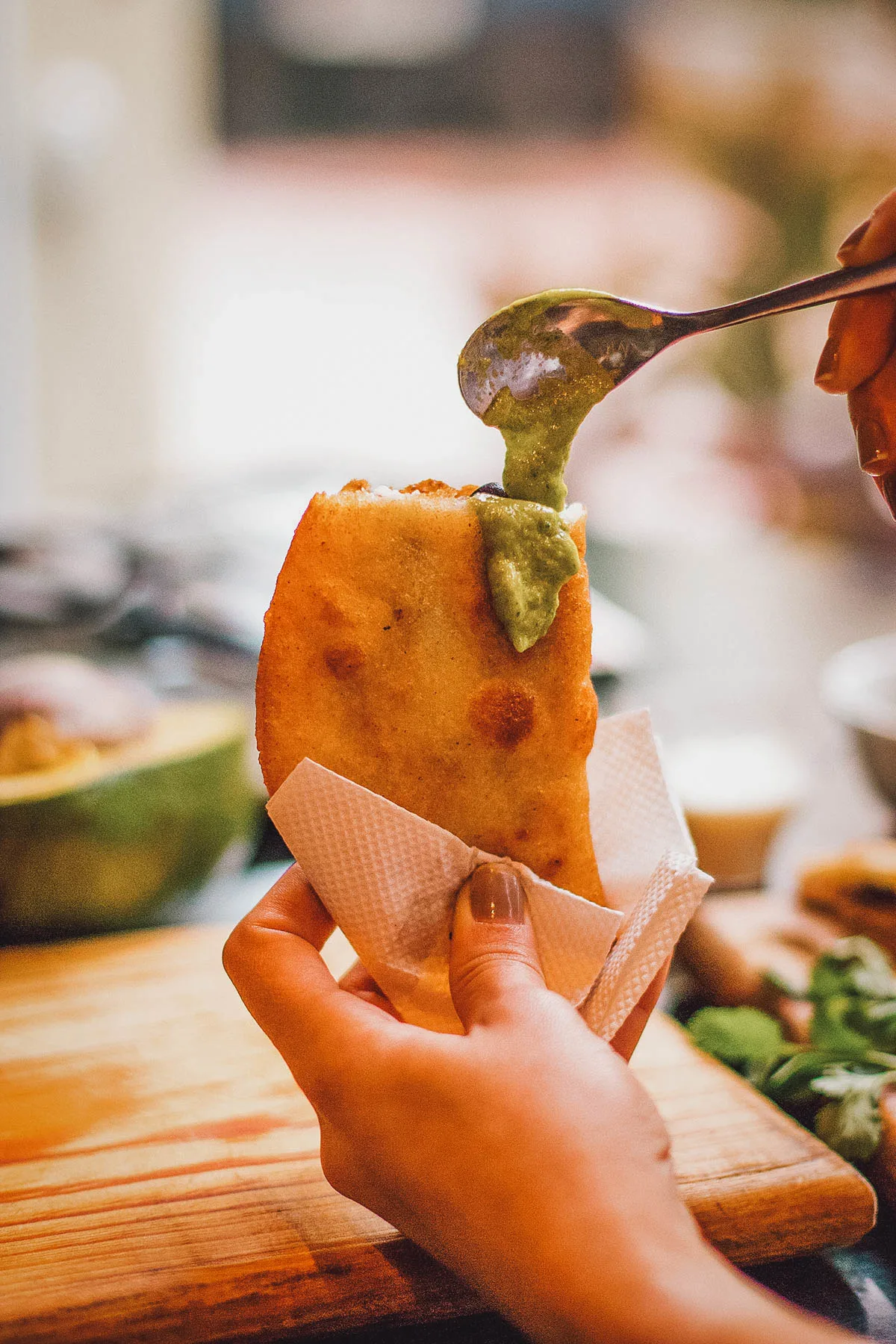 Venezuelan Food Woman pouring sauce into an empanada