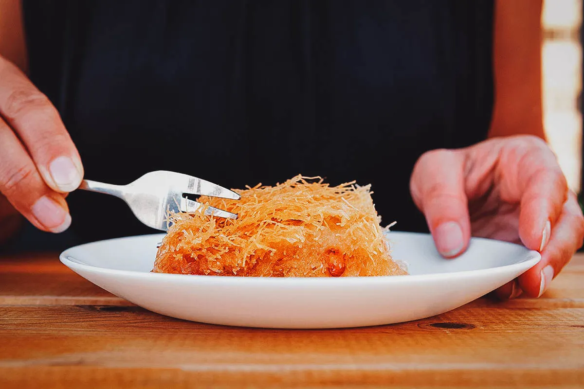 Woman eating kadaif, an Albanian dessert made with shredded phyllo dough