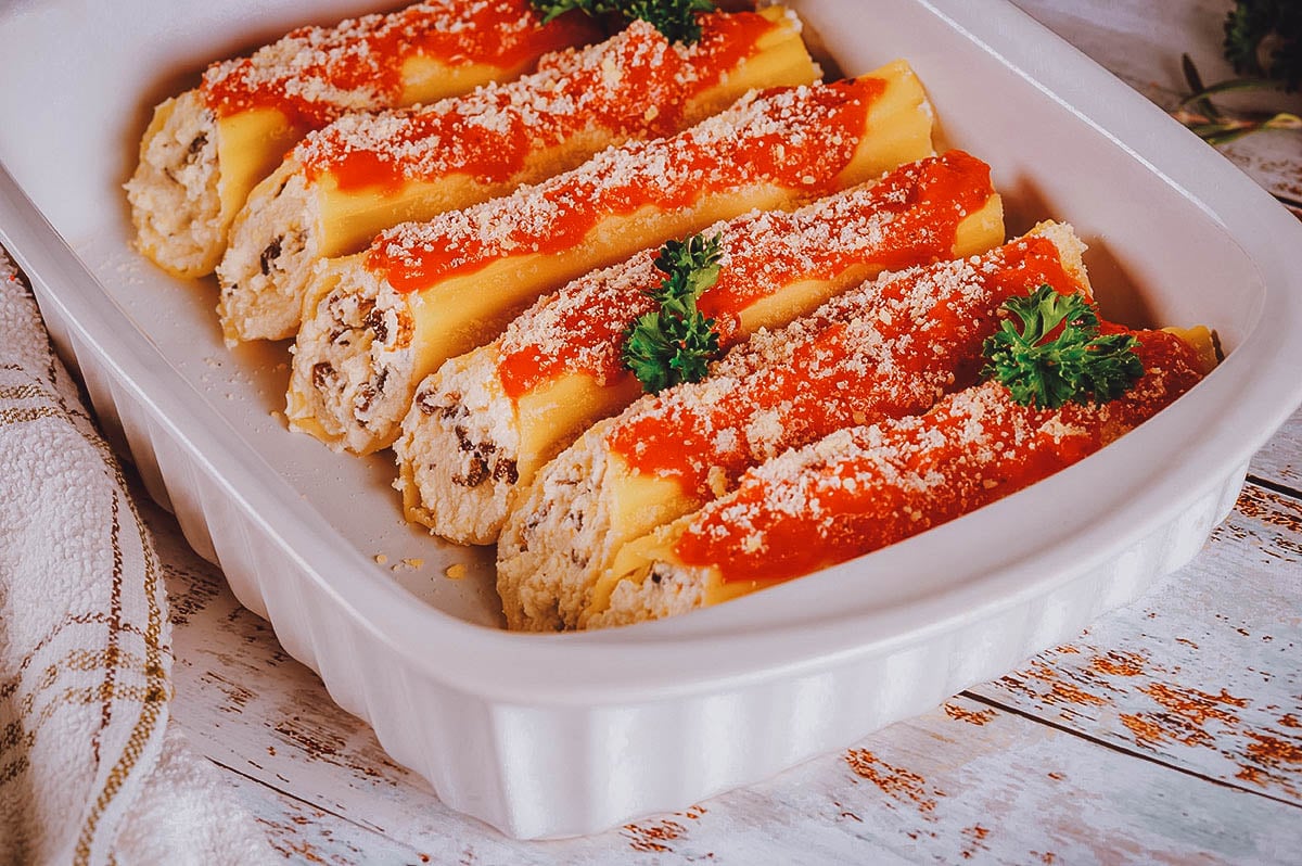 Platter of canelones topped with cheese and sauce, the Argentinian version of cannelloni