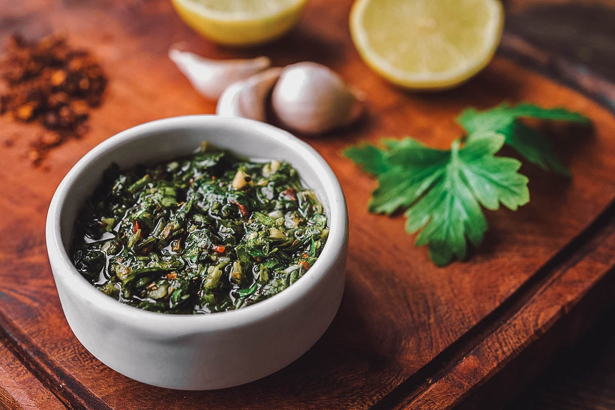 Small bowl of chimichurri made with chopped parsley, olive oil, and other ingredients