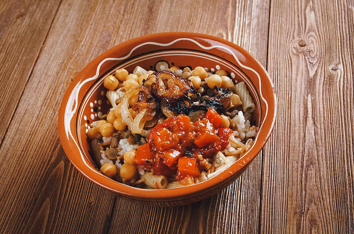 Egyptian Food Earthenware pot of kushari, an Egyptian food favorite made with lentils, fried onions, and a garlic-vinegar tomato sauce