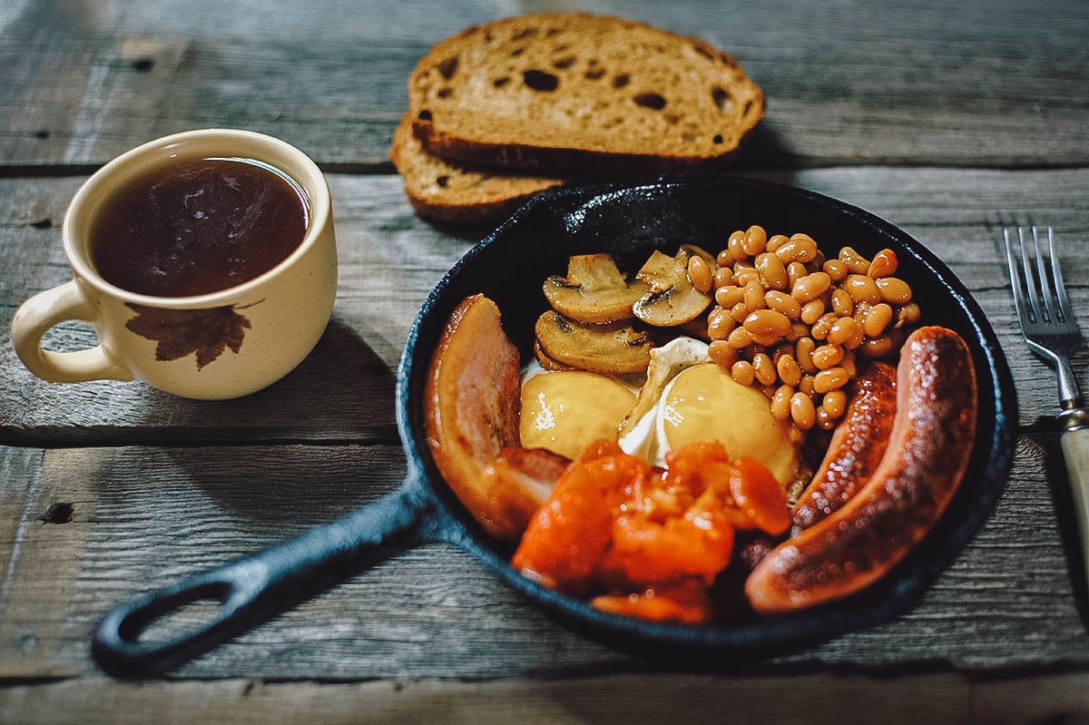 Full Irish breakfast with black pudding, fried egg, tomatoes, mushrooms, baked beans, Irish bacon, Irish brown bread, potato bread, and Irish coffee