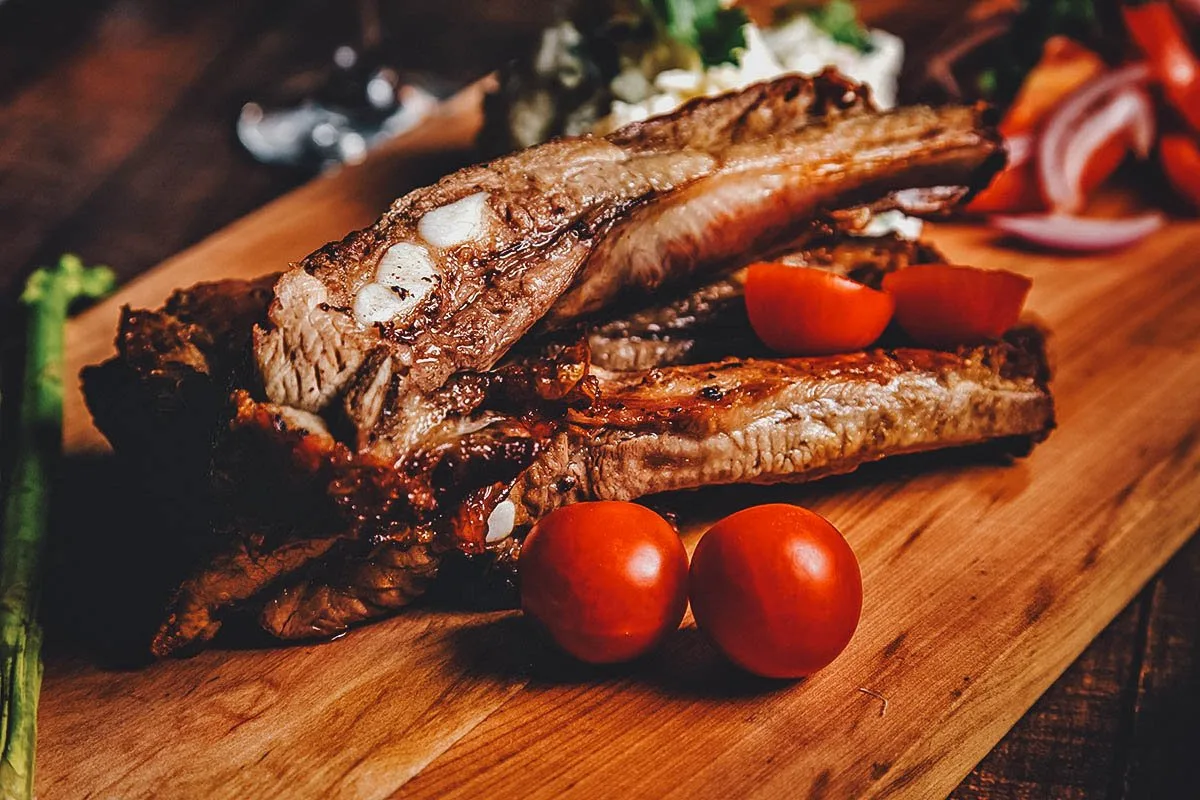 Chilean Food Costillar de chancho on a chopping board with tomatoes