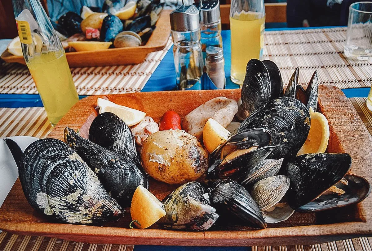 Chilean Food Curanto, a traditional seafood and meat dish served hot with lemon wedges