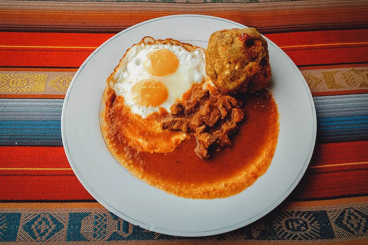 Ecuadorian Food Bolon de verde with chicharrones, hot sauce, and a fried egg