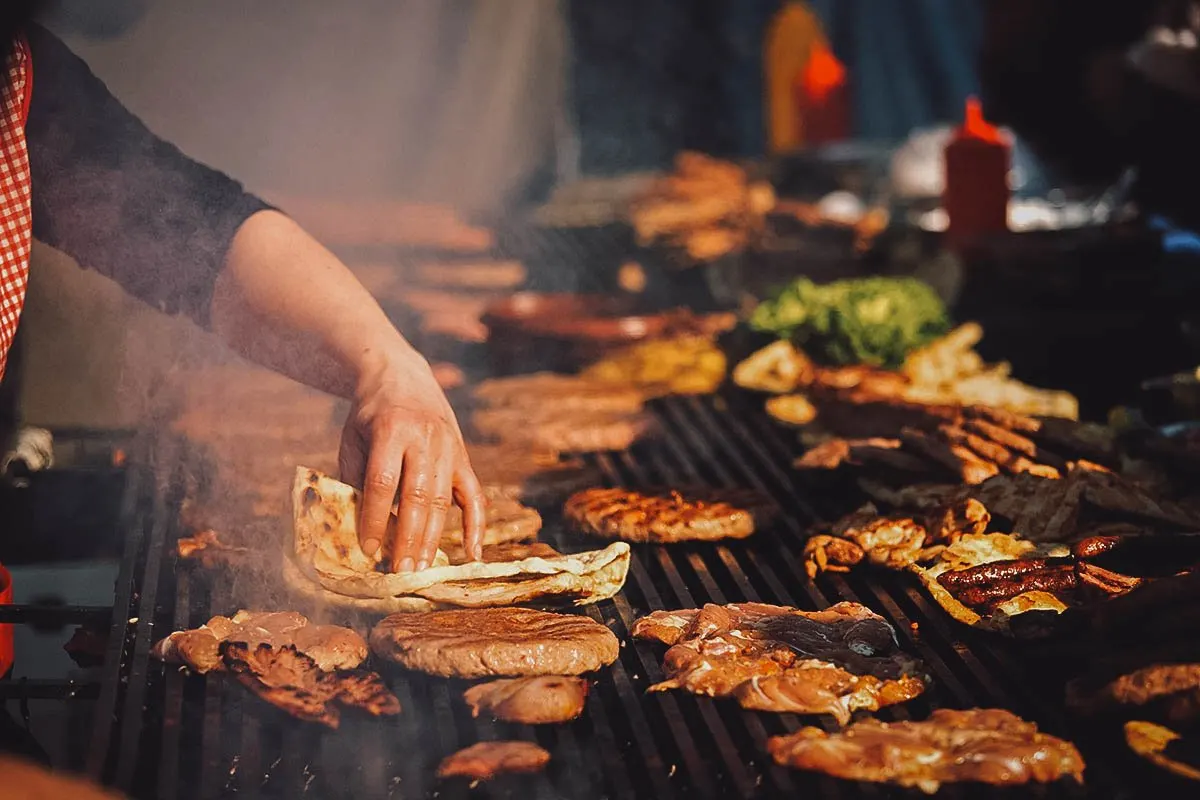 Woman preparing grilled meats for a rostilj or Serbian barbecue