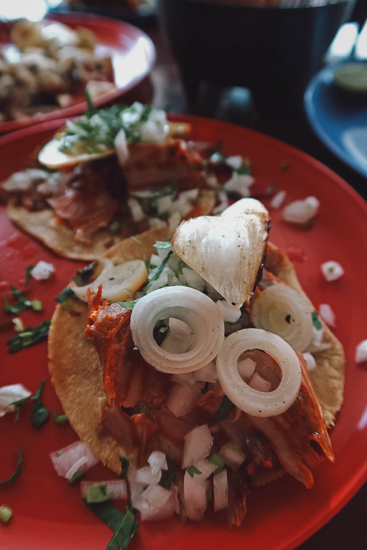 Pastor tacos topped with cebollitas