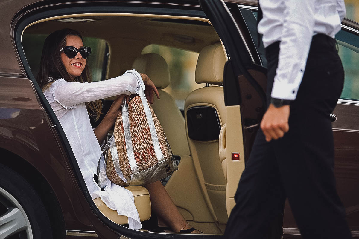 Chauffeur opening car door for woman