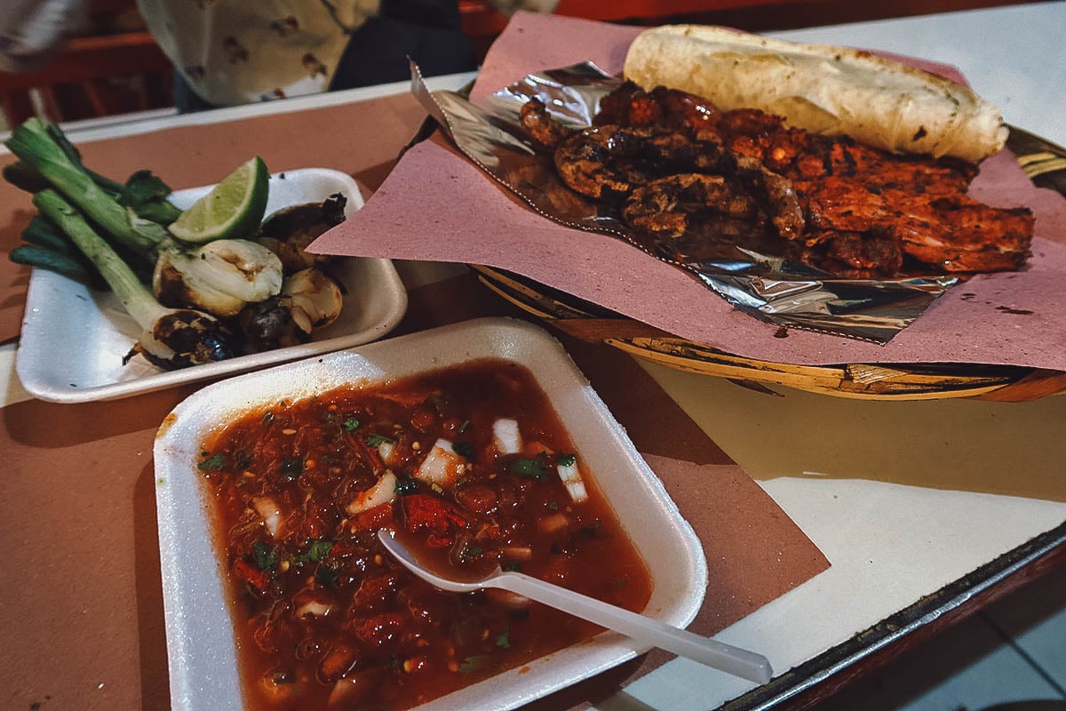 Basket of grilled meat with sides and corn tortillas