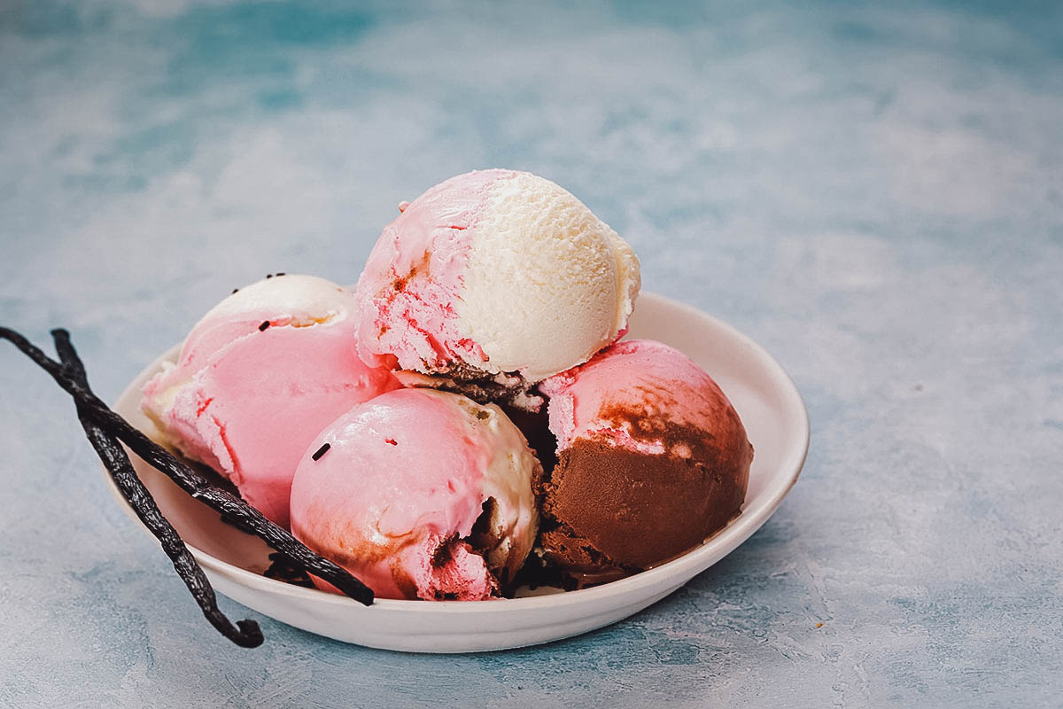 Pink strawberry and coconut ice cream scoops on plate stock photo