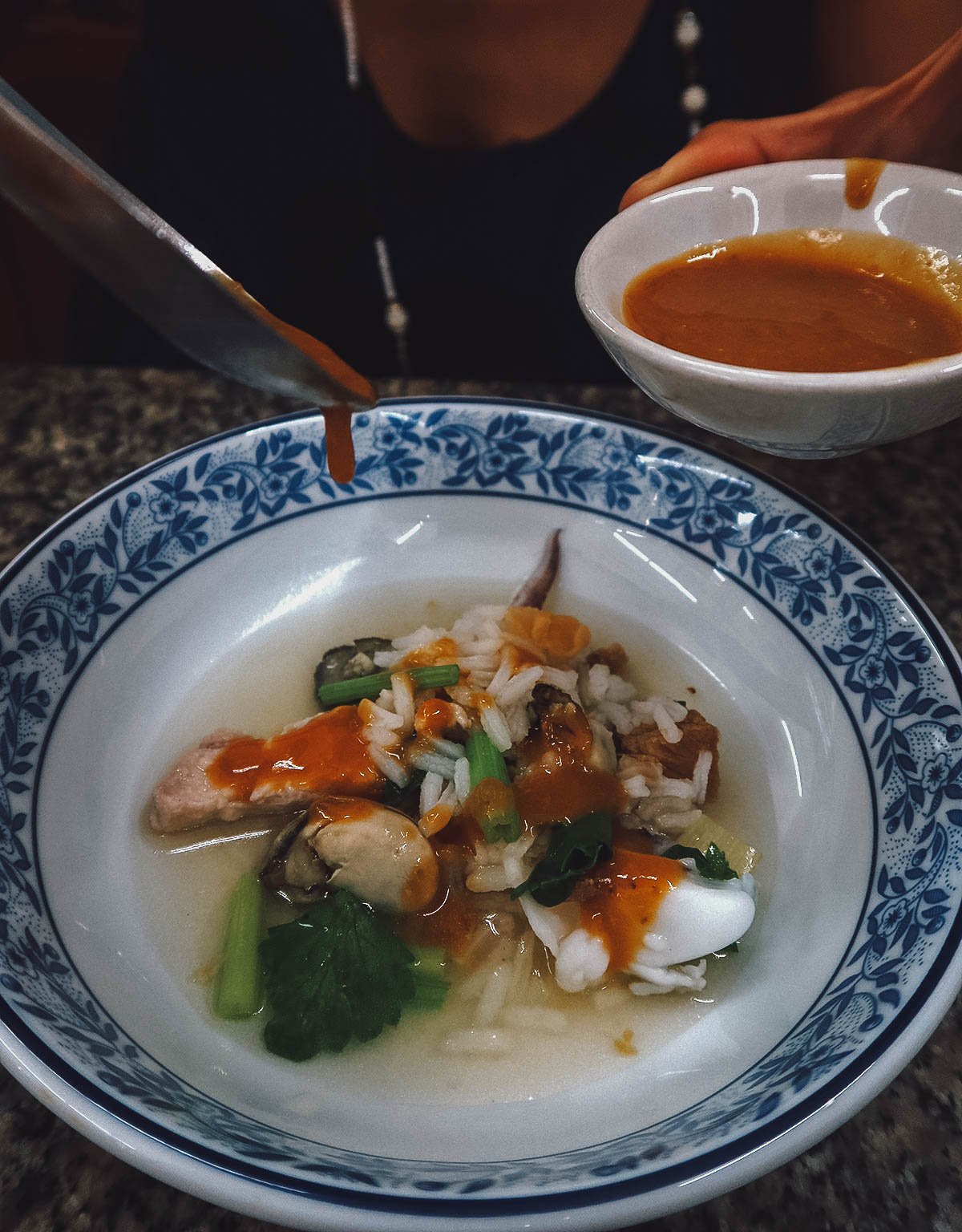 Pouring sauce over seafood porridge in Bangkok
